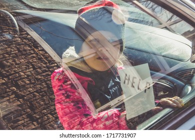 The Child In The Car Holds A Note With The Word Help