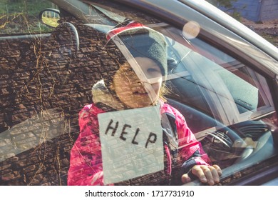 The Child In The Car Holds A Note With The Word Help