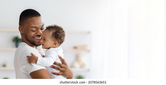 Child Care. Portrait Of Happy African American Father With Infant Baby In Arms Standing Near Window At Home, Young Black Dad Spending Time With Adorable Toddler Child, Panorama With Copy Space