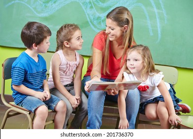 Child Care Worker And Children Reading A Picture Book Together In A Kindergarten