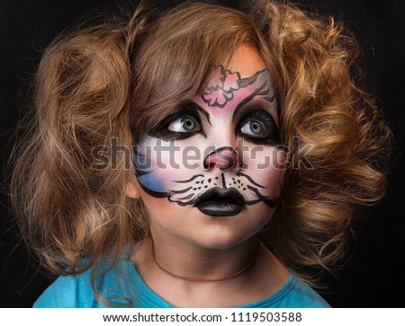 child with cat face painting. professional makeup. studio close up portrait of blonde girl with body art