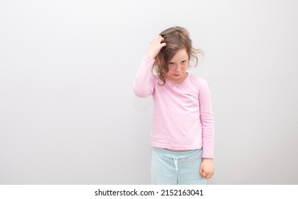 Child, Caucasian 6 Years Old, In A Pink Coat On A Gray Background. The Child In Thought Scratches His Head With His Hands, Emotions On His Face.