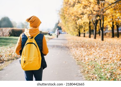 Child Caucasian Teen Boy In Yellow Beany Hat And Backpack Walking Outdoors With Laptop. Fall Autumn. Remote Or Distant Learning On The Go. Back To School. Homeschooling. Video Call. Copy Space.