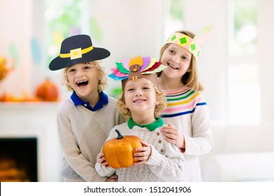 Child celebrating Thanksgiving. Kid in paper turkey hat, native American and pilgrim costume. Autumn fun crafts and art. Little boy and girl in decorated living room. Fall season pumpkin decoration.