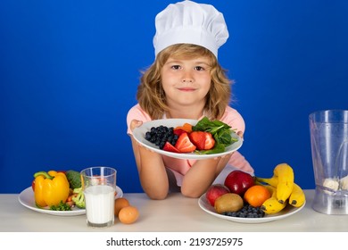 Child Chef Cook Hold Plate With Fruits Prepares Food In Isolated Blue Studio Background. Kids Cooking. Teen Boy With Apron And Chef Hat Preparing A Healthy Vegetables Meal In The Kitchen.