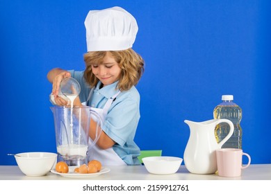 Child Chef Cook Prepares Food In Isolated Blue Studio Background. Kids Cooking. Teen Boy With Apron And Chef Hat Preparing A Healthy Vegetables Meal In The Kitchen.