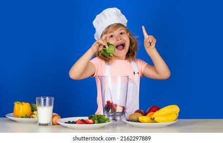 Child Chef Cook Prepares Food In Isolated Blue Studio Background. Kids Cooking. Teen Boy With Apron And Chef Hat Hold Spinach Preparing A Healthy Vegetables Meal In The Kitchen.