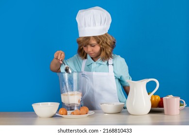 Child Chef Cook Prepares Food In Isolated Blue Studio Background. Kids Cooking. Teen Boy With Apron And Chef Hat Preparing A Healthy Vegetables Meal In The Kitchen.