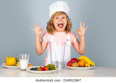 Child Chef Cook Prepares Food On Isolated Grey Studio Background. Kids Cooking. Teen Boy With Apron And Chef Hat Preparing A Healthy Vegetables. Excited Funny Chef Cook.