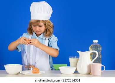 Child Chef Cook Prepares Food In Isolated Blue Studio Background. Kids Cooking. Teen Boy With Apron And Chef Hat Preparing A Healthy Vegetables Meal In The Kitchen.