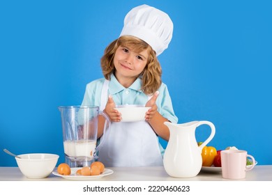 Child Chef Cook Prepares Food In Isolated Blue Studio Background. Kids Cooking. Teen Boy With Apron And Chef Hat Preparing A Healthy Vegetables Meal In The Kitchen.