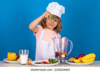 Child Chef Hold Broccoli Isolated On Blue. Funny Little Kid Chef Cook Wearing Uniform Cook Cap And Apron Cooked Food In The Kitchen.