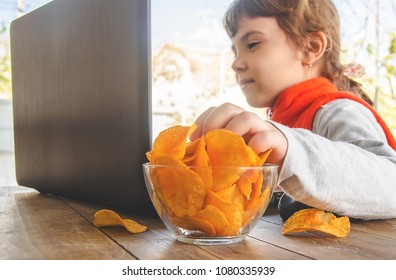child with chips behind a computer. selective focus. 