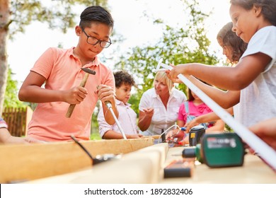 Child with chisel tool in summer workshop while chiseling wood