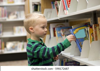 Child Choosing A Children's Reading Book From The Shelf At The Library.