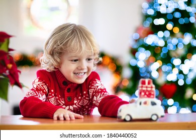 Child With Christmas Present. Kid With Xmas Gift. Little Boy Playing With A Toy Car Under Christmas Tree. Decorated Home For Winter Holidays. Celebration With Children. Kids Play.