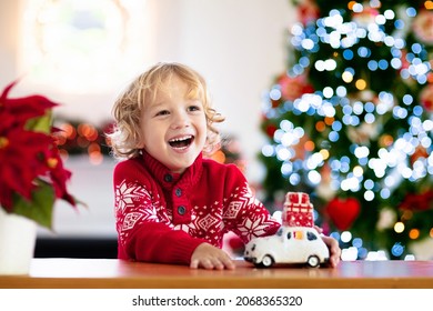 Child with Christmas present. Kid with Xmas gift. Little boy playing with a toy car under Christmas tree. Decorated home for winter holidays. Celebration with children. Kids play. - Powered by Shutterstock