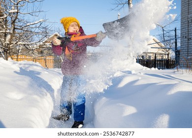 child clears path from snow in backyard of house in winter in village with shovel. snow removal.