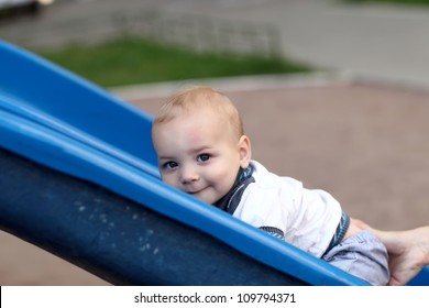 Child Is Climbing Up A Slide At Playground