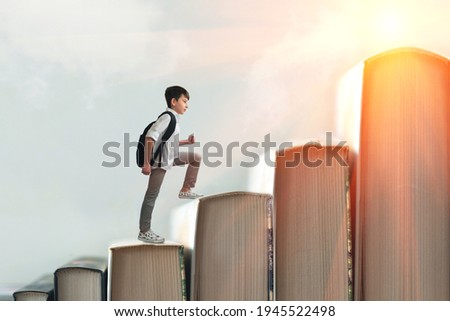 Child climbing stairs made of on sky background. Education or hard study concept. Soft focus