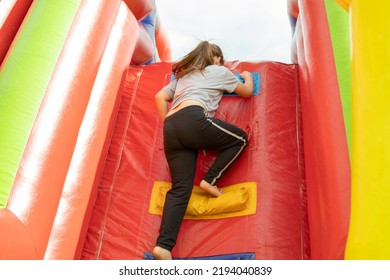 Child Climbs Slide. Child On Obstacle Course. Inflatable Structure In Park Of Detachments. Children's Play.