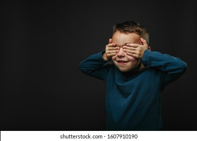 Child Closed His Eyes And Dreams Of Not Looking At Camera Isolated On Blank Gray Studio Background, Young Boy Posing For Portrait.