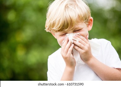 Child With A Cold Sneezing And Holding Tissue On His Nose