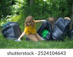 Child collecting trash outside. Ecology concept. Environmental pollution. Earth Day. Recycle waste litter rubbish garbage trash junk clean. Nature cleaning. Environment plastic pollution.