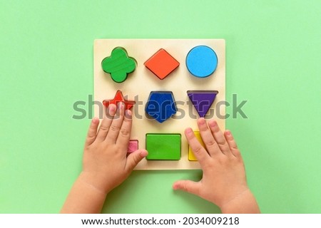 The child collects a multicolored wooden sorter. Educational logic toy for kid's. Top view.