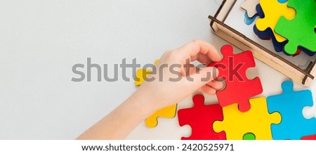 A child collects puzzles. Close-up of a child's hand holding a puzzle. Concept for Autism Awareness Day. Copy space.