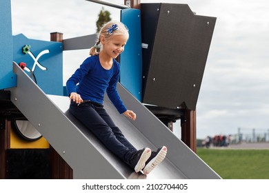 Child Coming Down Playground Slide. Happy Children Playing On Playground