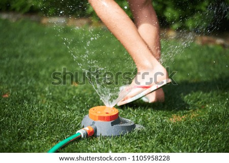 child cools down with lawn sprinkler