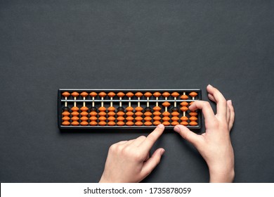 Child counting on soroban abacus. Black background with copy space. Concept education, school arithmetic, calculating thinking