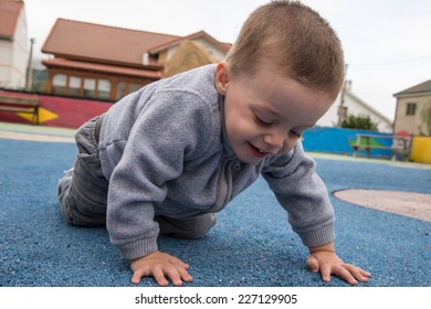 child crawling around on the floor of a playground