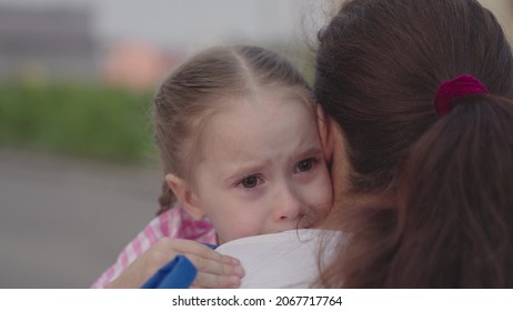 a child cries hugging her mother, small upset kid drops tears on her mother's shoulder, a woman calms her tear-stained daughter, tears from her eyes flow down girl's face, childish feelings of guilt