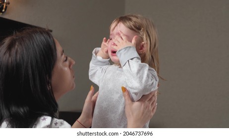 Child is crying in room in the arms of his mother. Mom calms child. Family mother and baby with tears in their eyes emotionally embrace their mother. A loving young mother hugs and comforts her little