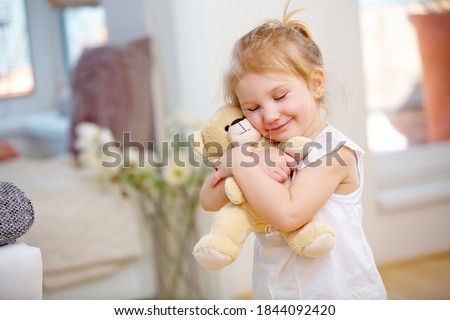 Child cuddles with her soft cuddly toy at home