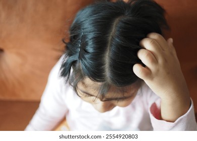 A Child with Curly Hair Engaged in Thought While Sitting on a Couch - Powered by Shutterstock