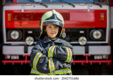 Niño, chico lindo, vestido con ropa de bomberos en una estación de bomberos con camión de bomberos, niños sueñan