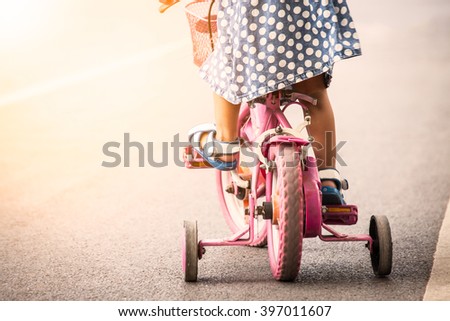 Child cute little girl riding bike in park