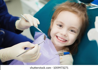 Child With Cute Smile Sits At Dentist Chair With Napkin