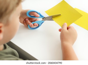 A child cuts colored paper with scissors. - Powered by Shutterstock