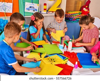Child cutting paper in class. Kids development and social lerning children in school. Children's project in kindergarten. Pictures into background