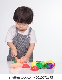 Child Cutting Vegetables And Fruits With Toy Knife Isolated On White Background.