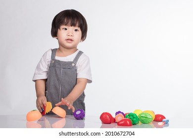 Child Cutting Vegetables And Fruits With Toy Knife Isolated On White Background.