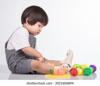 Child Cutting Vegetables And Fruits With Toy Knife Isolated On White Background.