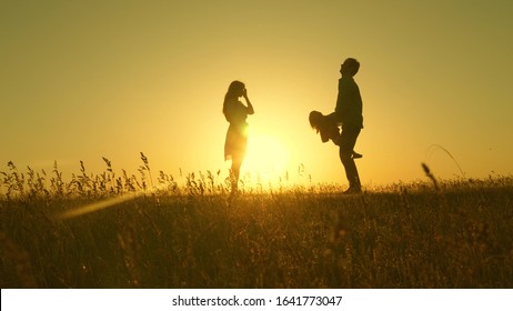 child, dad and mom play in meadow in the sun. concept of a happy childhood. mother, father and little daughter walking in a field in the sun. Happy young family. concept of a happy family. - Shutterstock ID 1641773047