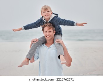 Child, Dad And Piggy Back On Beach On A Family Holiday Ocean Walk In Australia. Travel, Fun And A Portrait Of Happy Father And Son With Smile Playing On Sea Sand On Vacation With Open Sky And Waves.