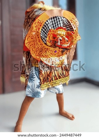 a child is dancing the barong, the barong is a creature in Balinese mythology that depicts goodness