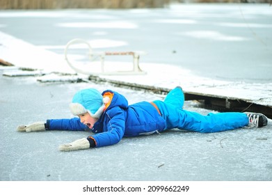 A Child In Danger On Thin Ice In Winter. The Boy Is Ice Skating On A Frozen Lake.